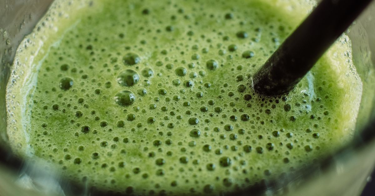 Close-up of a frothy green smoothie with bubbles and a straw for a fresh start.